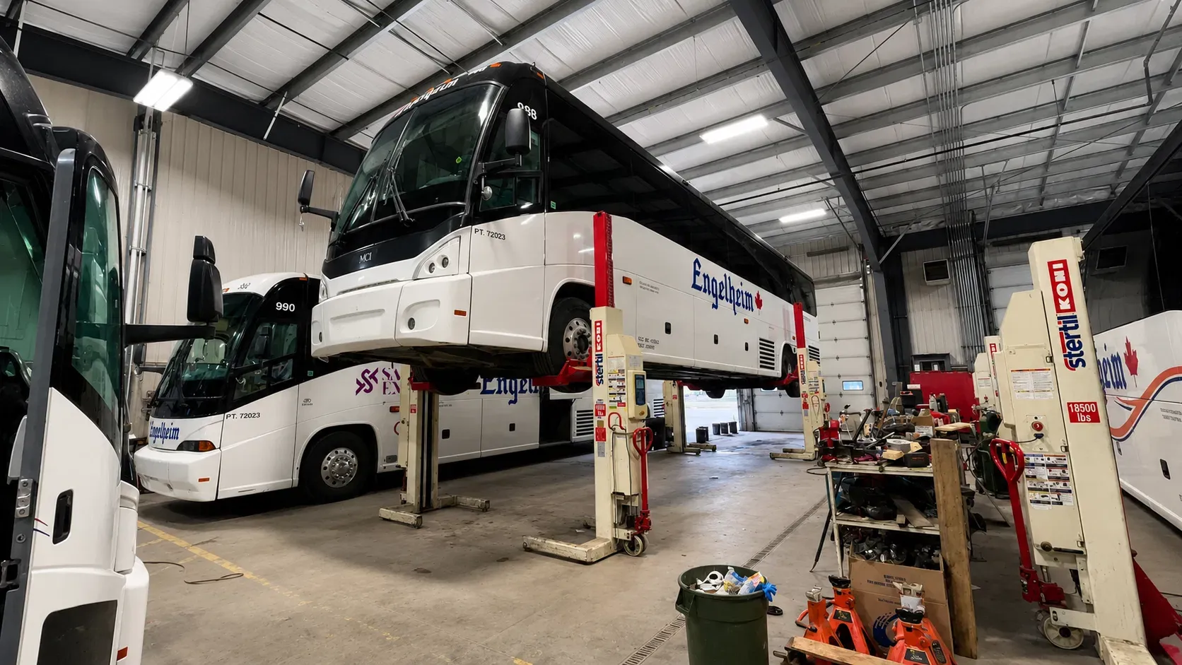 White fleet bus raised on a lift inside a professional Calgary maintenance facility